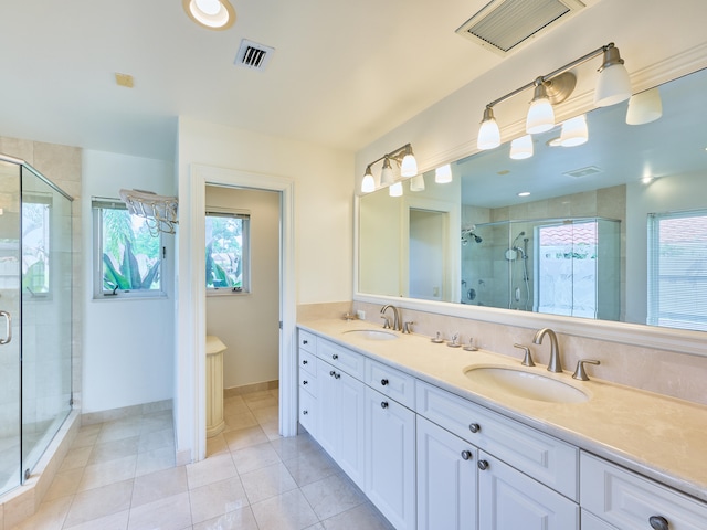 bathroom with plenty of natural light, a shower with shower door, tile floors, and dual vanity