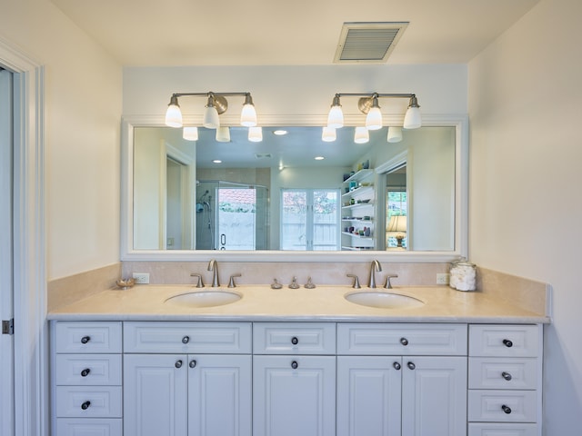 bathroom with a shower with shower door and dual vanity