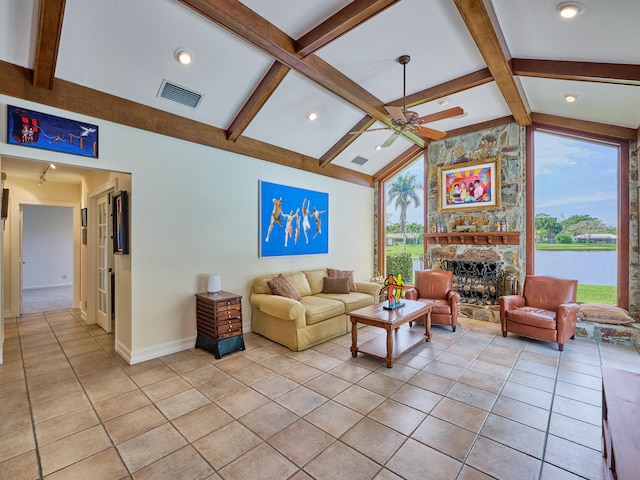 living room with light tile flooring, ceiling fan, vaulted ceiling with beams, and a stone fireplace