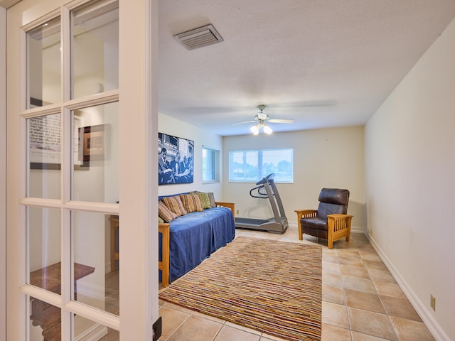 tiled bedroom featuring ceiling fan and a textured ceiling