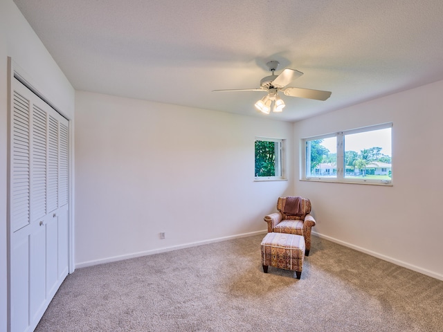 sitting room featuring a textured ceiling, ceiling fan, and carpet