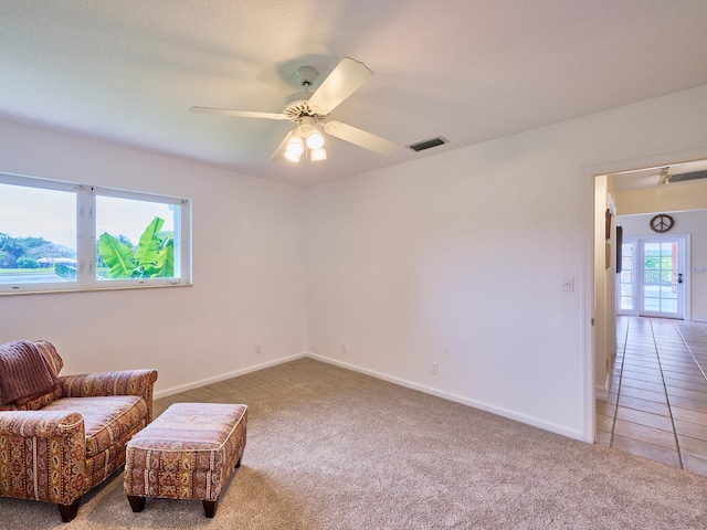 living area with light carpet and ceiling fan