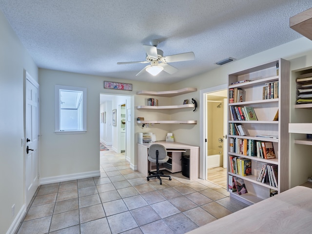 tiled office space with ceiling fan and a textured ceiling