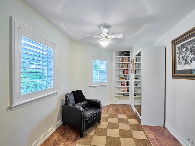 living area with built in features, light hardwood / wood-style floors, a healthy amount of sunlight, and ceiling fan