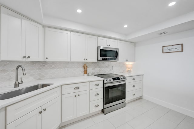 kitchen with stainless steel appliances, tasteful backsplash, white cabinets, sink, and light tile floors