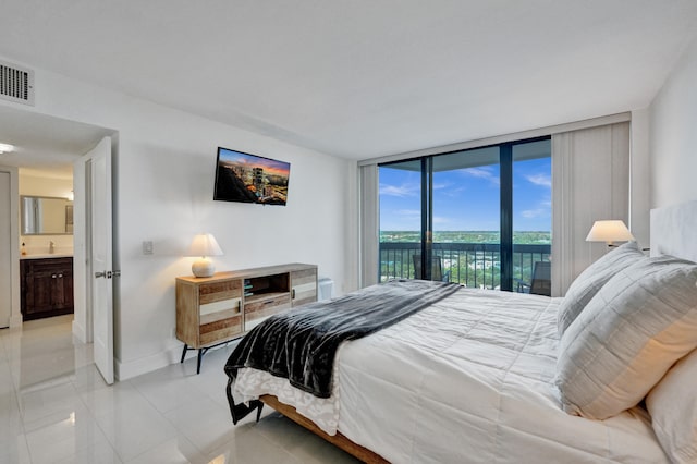 bedroom featuring a wall of windows, connected bathroom, access to outside, and light tile floors