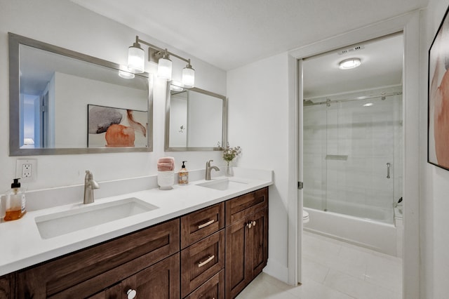 full bathroom featuring tile flooring, toilet, shower / bath combination with glass door, and double sink vanity