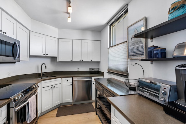 kitchen featuring white cabinetry, appliances with stainless steel finishes, sink, light hardwood / wood-style flooring, and rail lighting