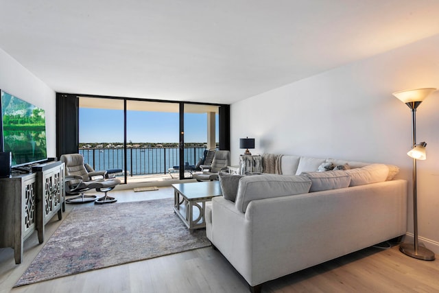 living room featuring hardwood / wood-style floors, floor to ceiling windows, and a water view