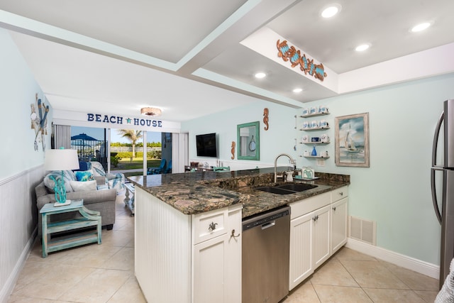 kitchen featuring white cabinetry, stainless steel appliances, light tile floors, sink, and dark stone countertops