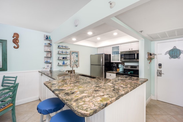 kitchen with white cabinets, sink, stainless steel appliances, and kitchen peninsula