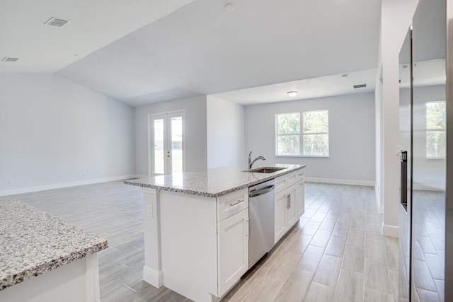 kitchen featuring white cabinetry, light stone counters, sink, and an island with sink