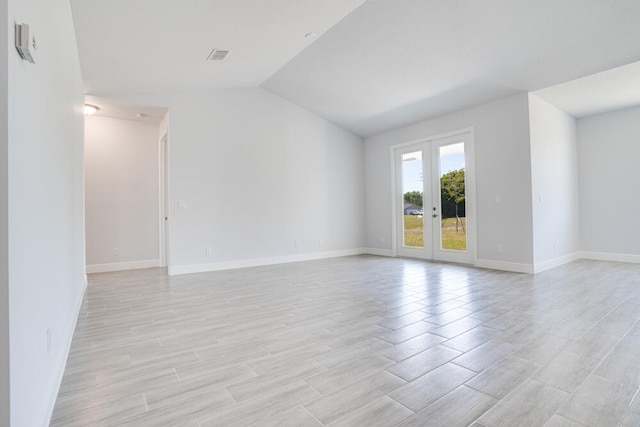 unfurnished room with vaulted ceiling and french doors