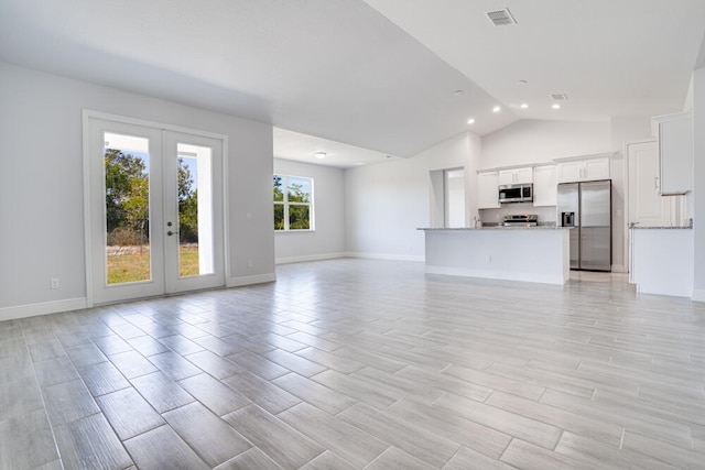 unfurnished living room featuring lofted ceiling and french doors