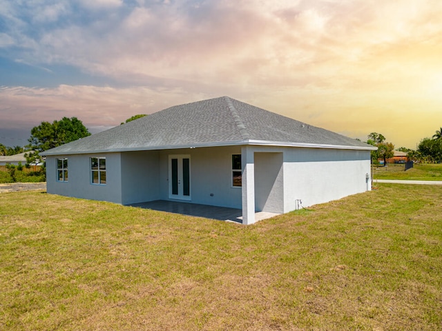 back house at dusk with a yard and a patio area