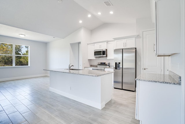 kitchen featuring white cabinets, vaulted ceiling, stainless steel appliances, and light stone countertops