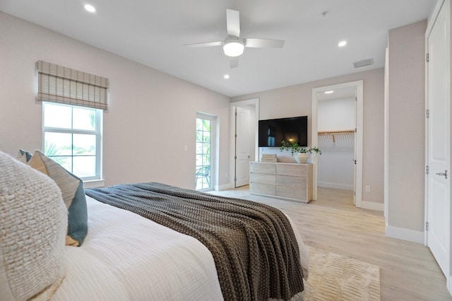 bedroom featuring ceiling fan, a closet, light wood-type flooring, and multiple windows