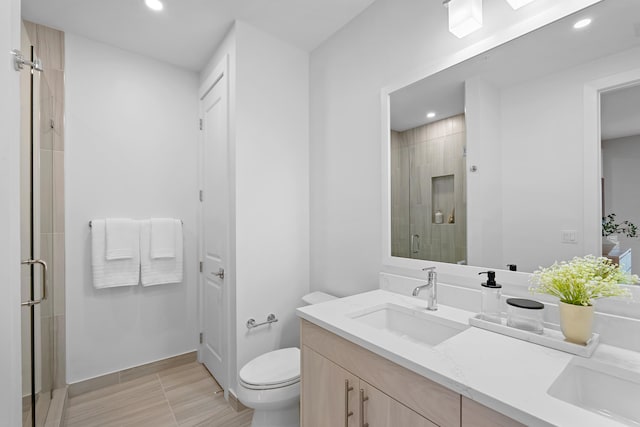 bathroom with a shower with door, vanity, and toilet