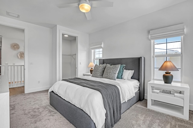 bedroom featuring a closet, baseboards, carpet flooring, a walk in closet, and visible vents