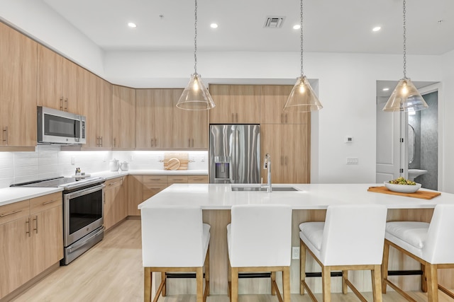 kitchen featuring stainless steel appliances, a sink, light brown cabinets, and modern cabinets