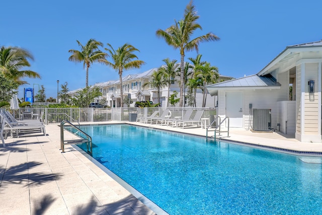 pool with cooling unit, a patio, a residential view, and fence