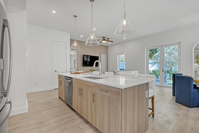 kitchen with light wood-type flooring, dishwasher, open floor plan, french doors, and light brown cabinets