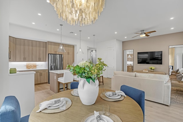 dining room with light wood-style flooring, ceiling fan with notable chandelier, and recessed lighting