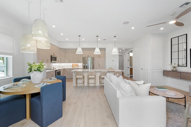 living room featuring ceiling fan and light hardwood / wood-style floors