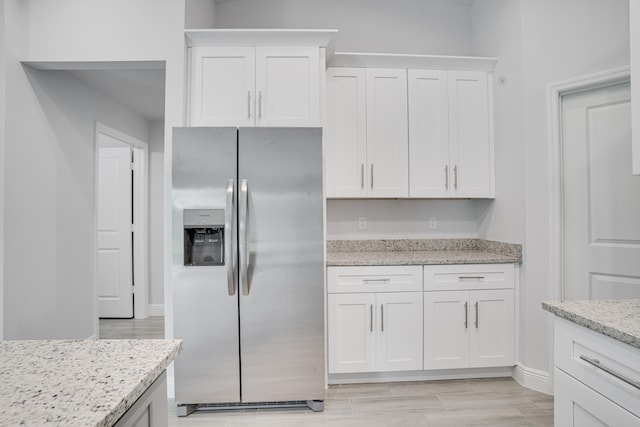 kitchen featuring stainless steel fridge with ice dispenser, white cabinets, light stone countertops, and light hardwood / wood-style flooring