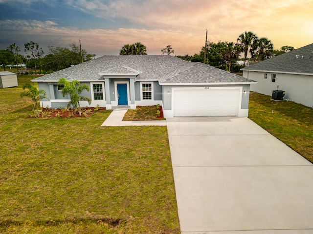 single story home featuring central AC unit, a yard, and a garage