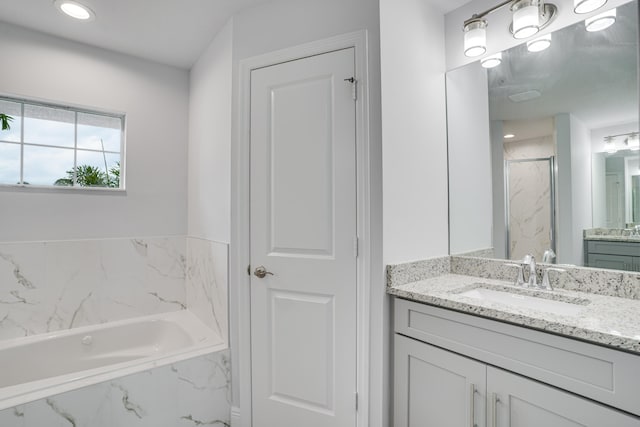 bathroom featuring a relaxing tiled bath and vanity