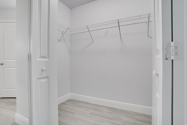 walk in closet with light hardwood / wood-style floors