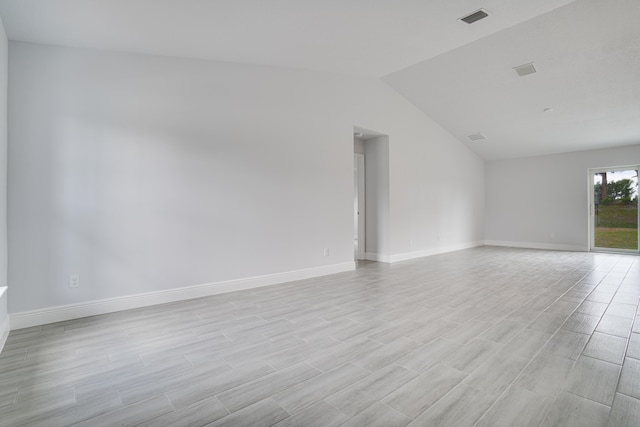 empty room with light hardwood / wood-style flooring and vaulted ceiling