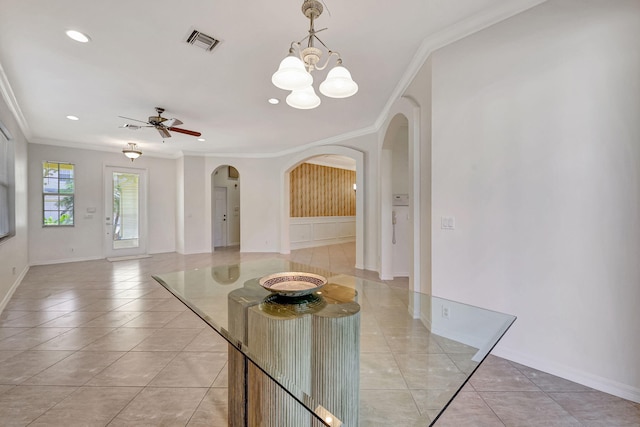 dining area featuring ceiling fan with notable chandelier, light tile floors, and crown molding