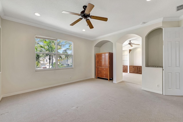 empty room with ornamental molding, ceiling fan, and carpet flooring