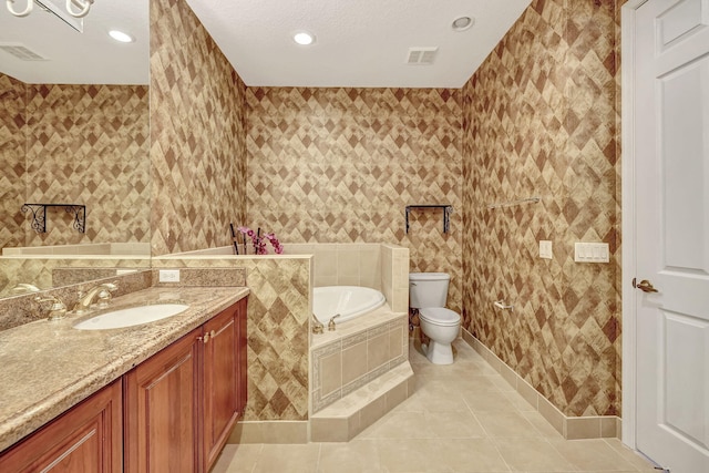 bathroom with tiled bath, oversized vanity, tile flooring, toilet, and a textured ceiling