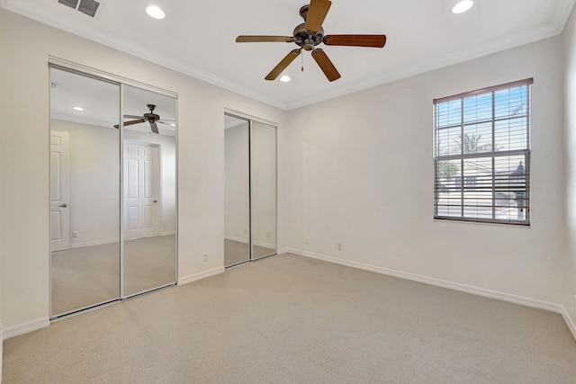 unfurnished bedroom with multiple closets, carpet floors, ceiling fan, and crown molding