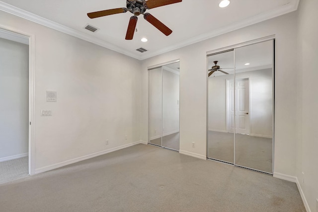 unfurnished bedroom featuring ornamental molding, carpet flooring, ceiling fan, and two closets