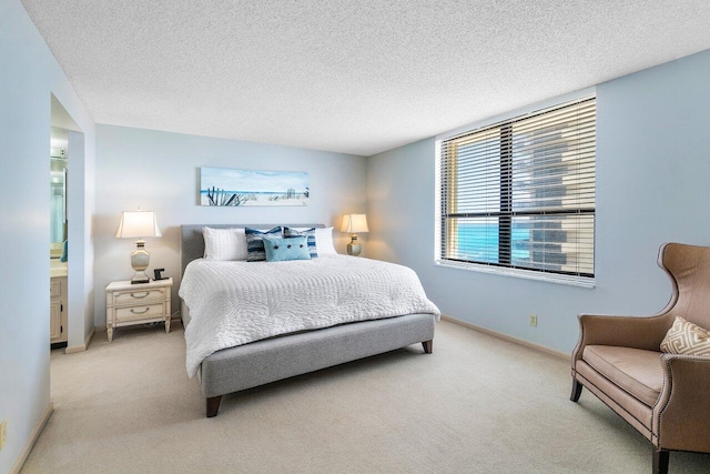 carpeted bedroom featuring a textured ceiling and ensuite bath