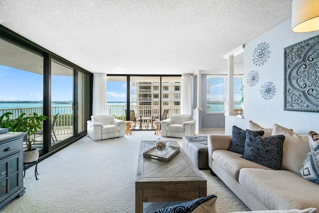 living room featuring a textured ceiling, a water view, plenty of natural light, and expansive windows