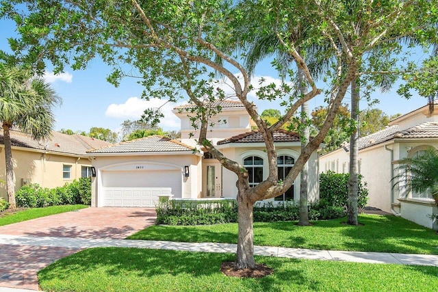 mediterranean / spanish-style house featuring a garage and a front lawn