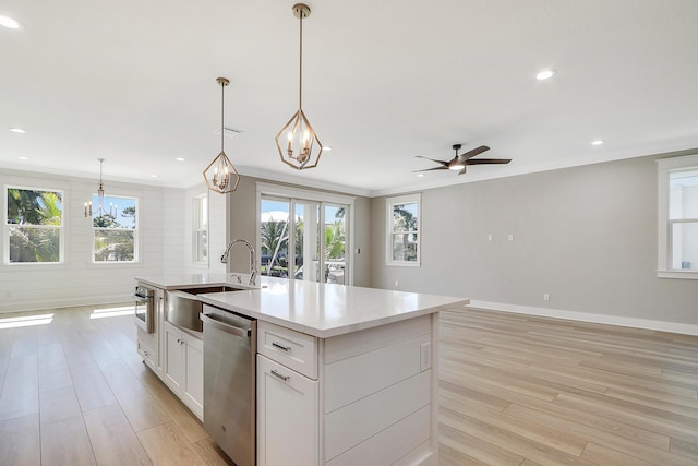 kitchen with dishwasher, a center island with sink, ceiling fan, decorative light fixtures, and white cabinetry