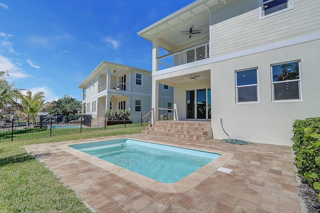 back of house with a balcony, ceiling fan, a patio area, and a lawn