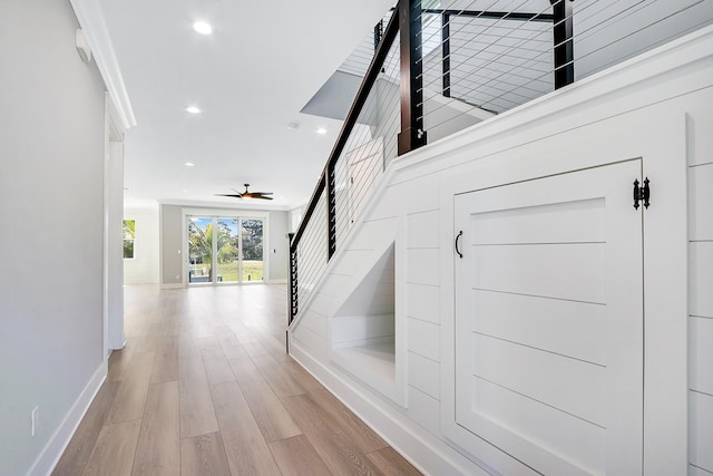 stairs featuring ceiling fan, hardwood / wood-style floors, and crown molding