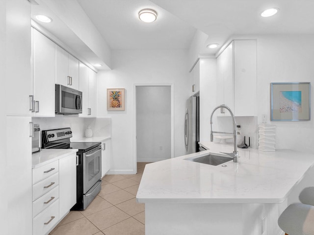 kitchen featuring stainless steel appliances, white cabinetry, a sink, and a peninsula