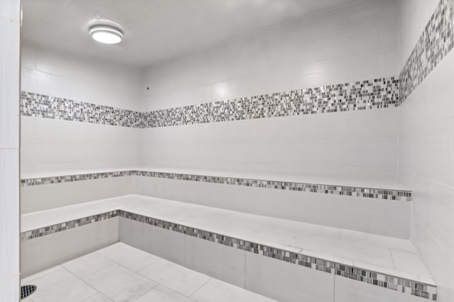 bathroom featuring a shower, tile flooring, and tile walls