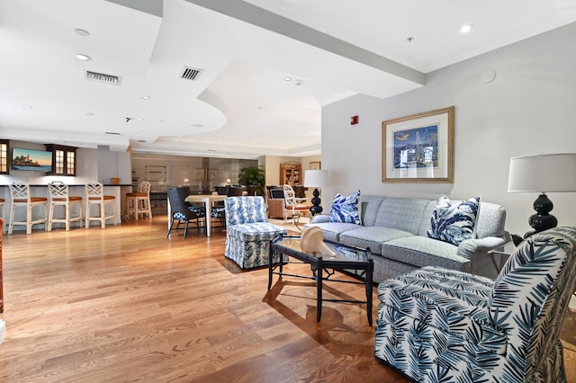 living room with crown molding and light hardwood / wood-style flooring