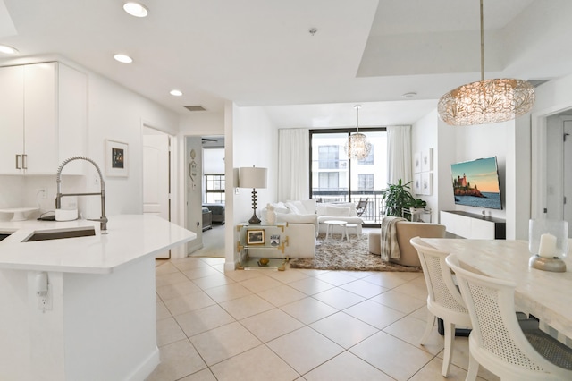 interior space featuring white cabinetry, decorative light fixtures, a notable chandelier, sink, and light tile floors