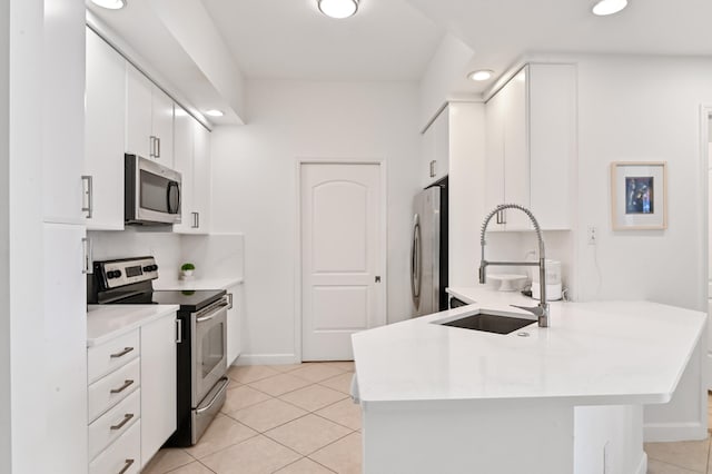 kitchen with appliances with stainless steel finishes, white cabinets, kitchen peninsula, sink, and light tile floors