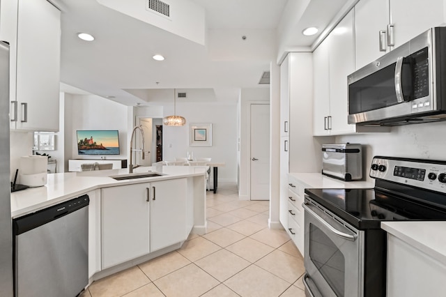 kitchen featuring appliances with stainless steel finishes, white cabinetry, hanging light fixtures, and sink